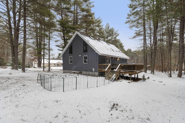 snow covered house with a wooden deck