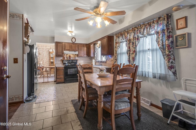 tiled dining room with ceiling fan and sink