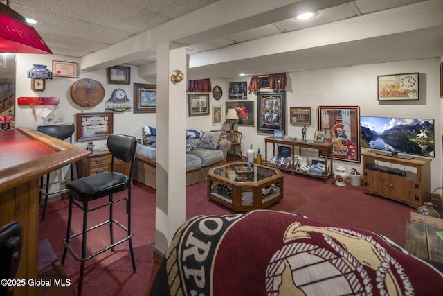 carpeted living room featuring a drop ceiling