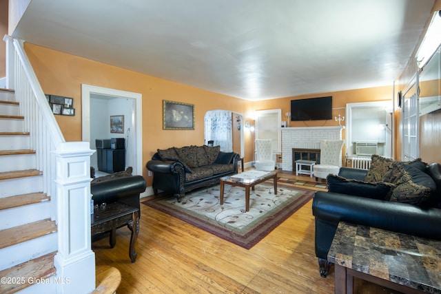 living room with light hardwood / wood-style floors and a brick fireplace