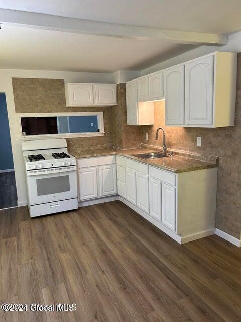 kitchen with dark wood-type flooring, white cabinets, sink, gas range gas stove, and beam ceiling