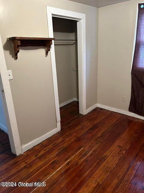 unfurnished bedroom featuring dark hardwood / wood-style floors and a closet