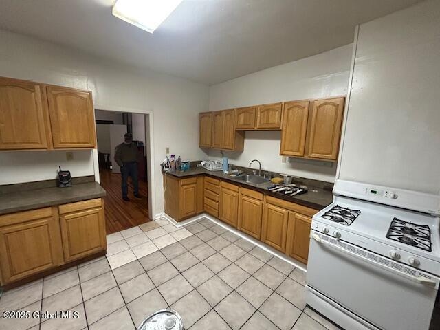 kitchen with sink, light tile patterned floors, and white stove