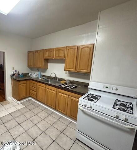 kitchen featuring light tile patterned flooring, white range with gas stovetop, and sink