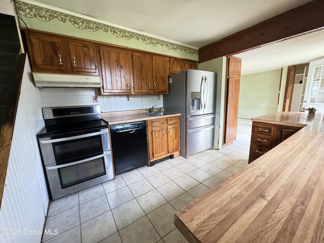 kitchen with decorative backsplash, stainless steel appliances, sink, light tile patterned floors, and butcher block countertops