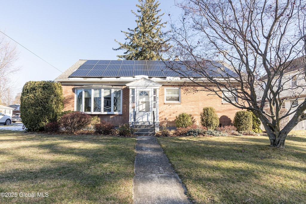 view of front of property featuring a front yard and solar panels