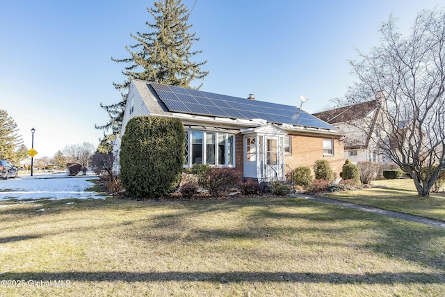 view of front of house featuring solar panels and a front lawn