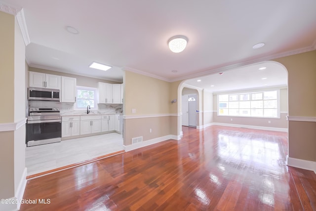 801 Holland Rd, Schenectady, NY 12303 - kitchen featuring appliances with stainless steel finishes, arched walkways, light countertops, white cabinets, and open floor plan