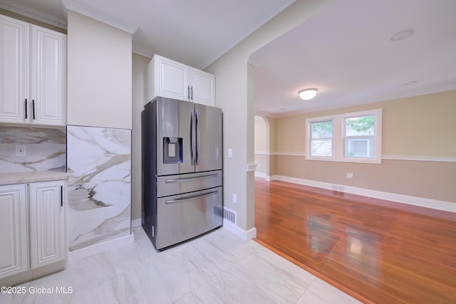 801 Holland Rd, Schenectady, NY 12303 - kitchen featuring stainless steel fridge, ornamental molding, white cabinetry, light stone countertops, and arched walkways