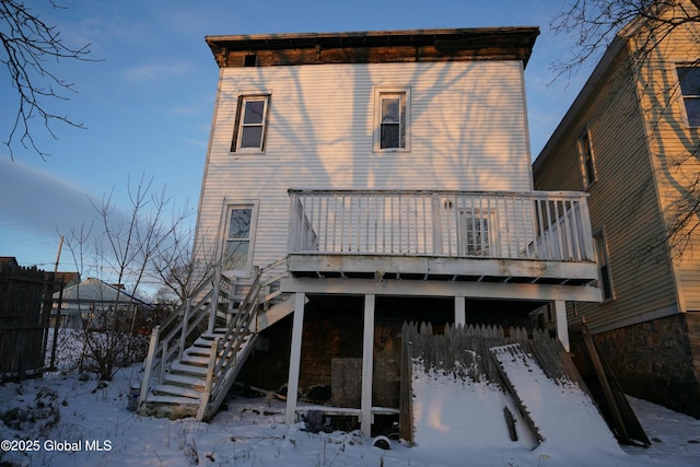 snow covered back of property featuring a deck