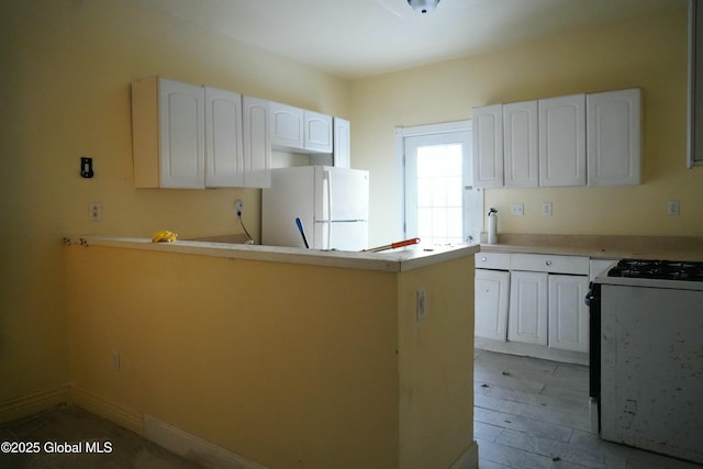 kitchen with white cabinets, white appliances, and kitchen peninsula