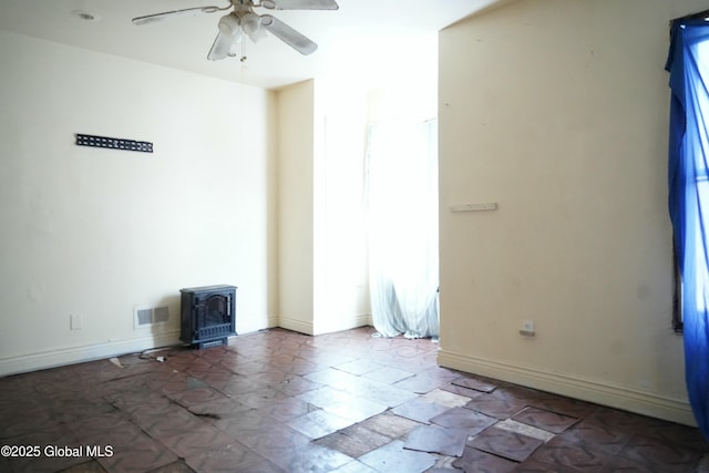 spare room featuring a wood stove and ceiling fan