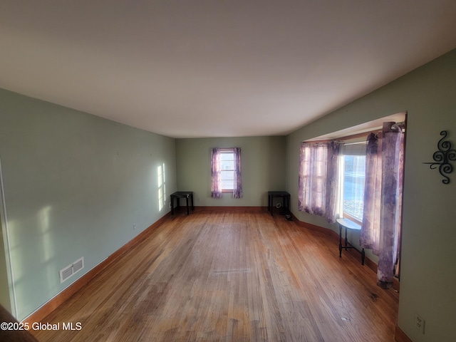 unfurnished living room featuring baseboards, visible vents, and light wood finished floors