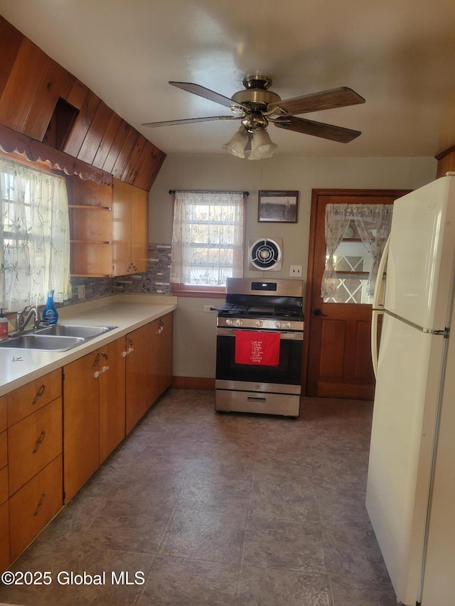 kitchen with ceiling fan, sink, stainless steel range, white refrigerator, and vaulted ceiling