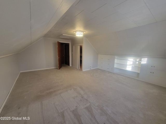 bonus room with lofted ceiling, light colored carpet, and built in features