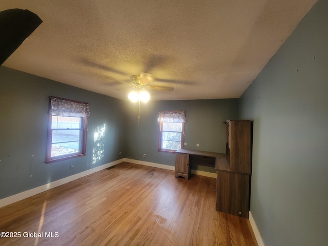 empty room featuring ceiling fan, light hardwood / wood-style flooring, a healthy amount of sunlight, and a textured ceiling