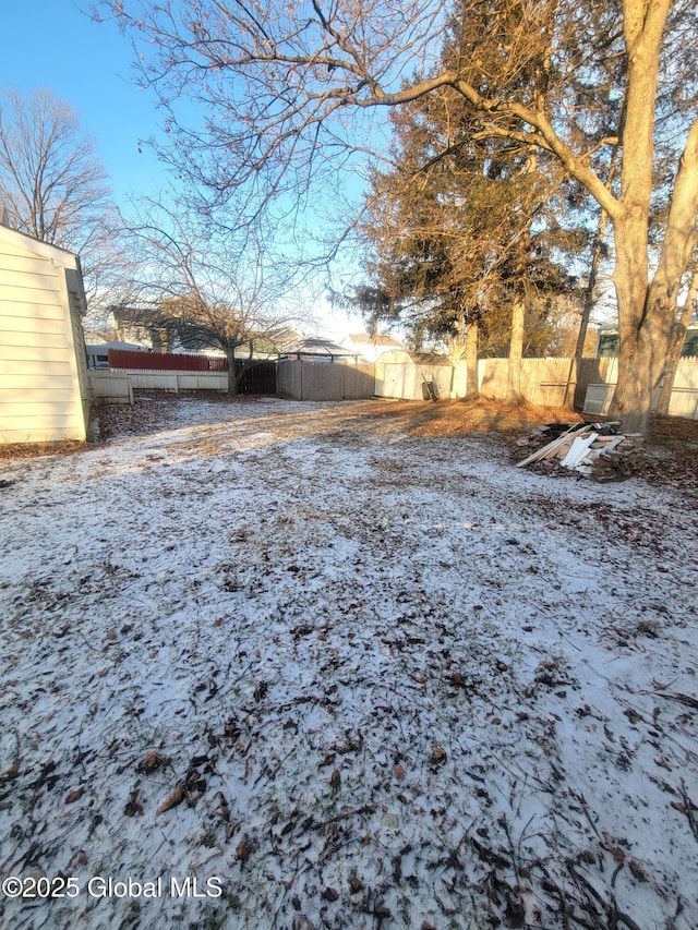 yard layered in snow featuring a storage unit and fence