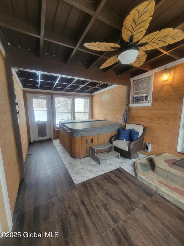 game room with dark wood-style floors, wood walls, and ceiling fan