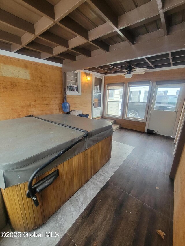 interior space with beam ceiling, ceiling fan, wooden walls, wood finished floors, and coffered ceiling