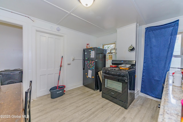 kitchen featuring white cabinets, black appliances, and light hardwood / wood-style floors