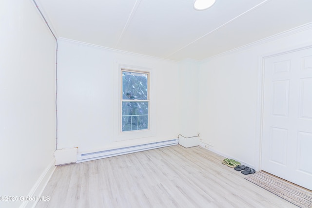 spare room featuring ornamental molding, baseboard heating, and light hardwood / wood-style flooring