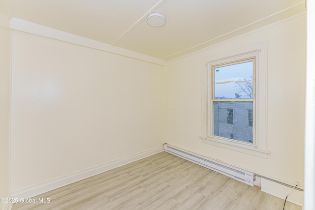 empty room featuring baseboard heating, crown molding, and light hardwood / wood-style flooring