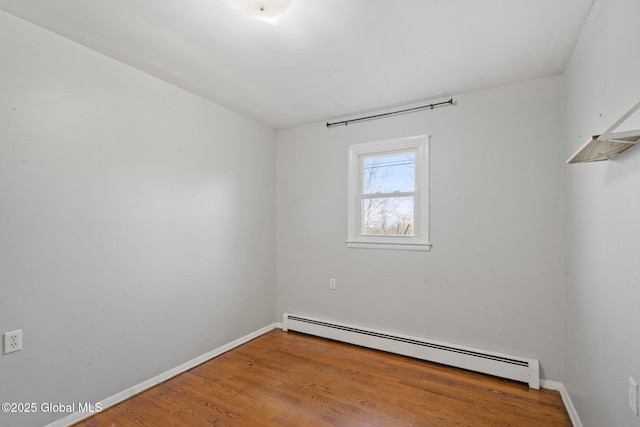 spare room with hardwood / wood-style floors and a baseboard heating unit