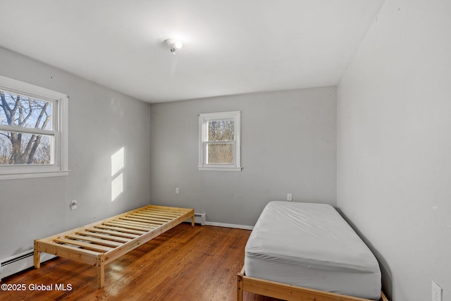 bedroom featuring hardwood / wood-style floors and a baseboard heating unit