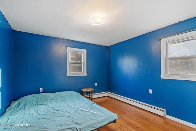 bedroom with hardwood / wood-style flooring and a baseboard heating unit