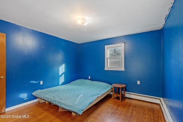 bedroom featuring baseboard heating and hardwood / wood-style floors