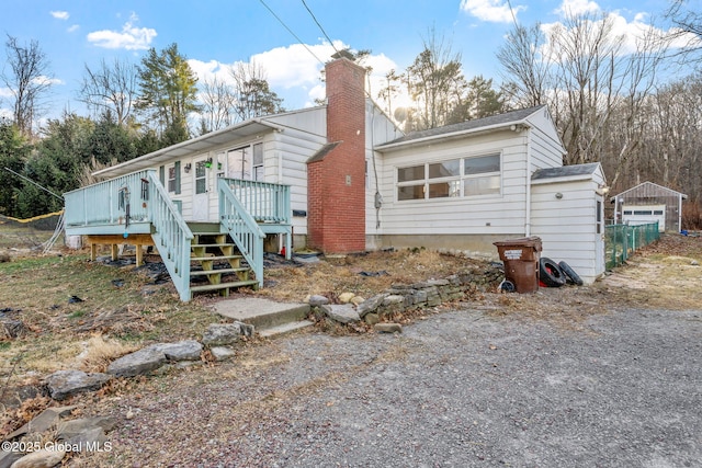 back of house with a deck, a garage, and an outdoor structure