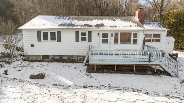 snow covered rear of property with a wooden deck