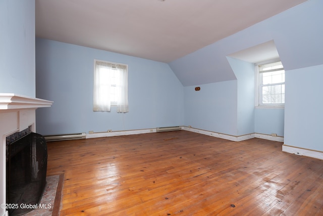 bonus room featuring a healthy amount of sunlight, light wood-type flooring, lofted ceiling, and a baseboard radiator