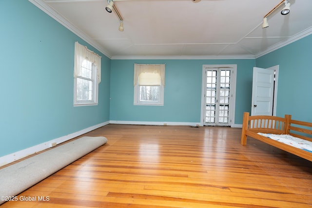 unfurnished bedroom featuring ornamental molding, rail lighting, and light hardwood / wood-style flooring