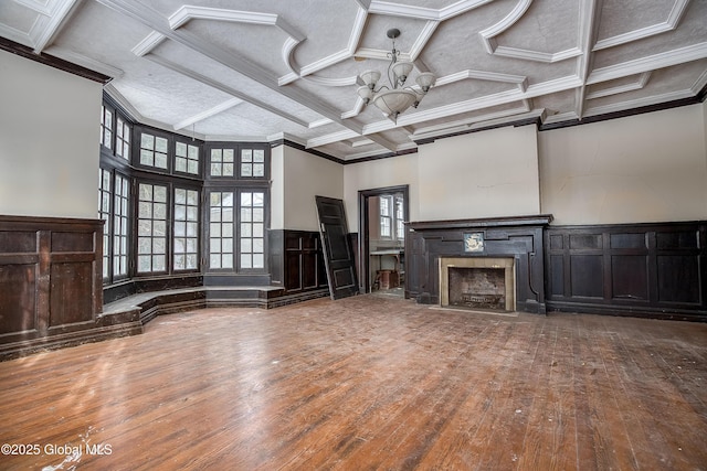 unfurnished living room with hardwood / wood-style floors, a notable chandelier, crown molding, and coffered ceiling