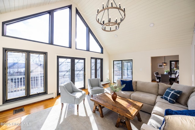 living room with baseboard heating, high vaulted ceiling, light hardwood / wood-style floors, and a notable chandelier