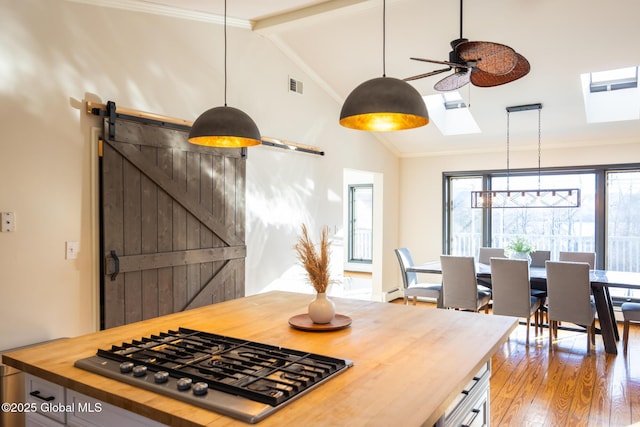 kitchen featuring stainless steel gas stovetop, wood counters, lofted ceiling, ceiling fan, and a barn door