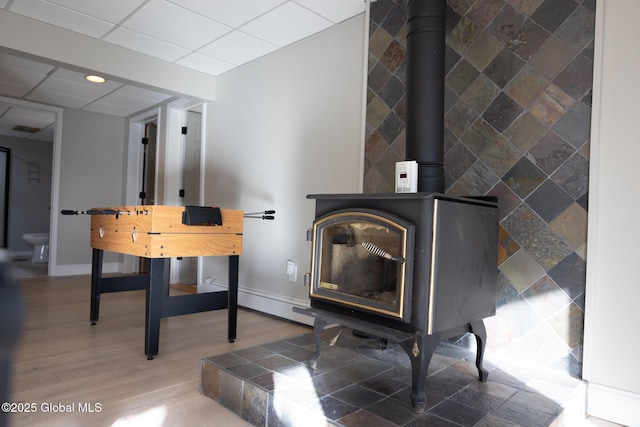 room details with hardwood / wood-style floors, a drop ceiling, and a wood stove