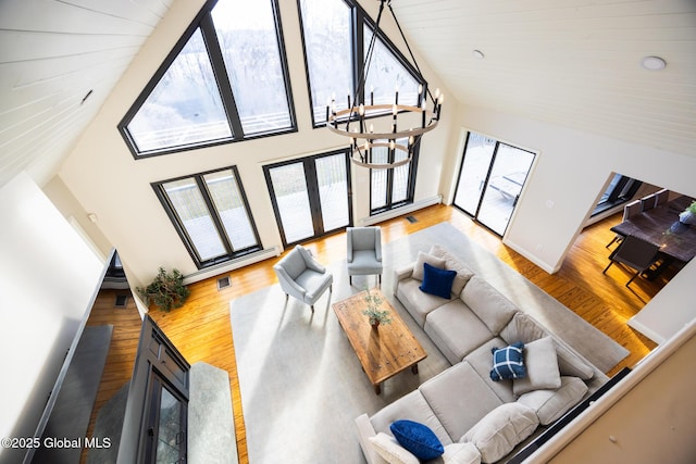 living room featuring plenty of natural light, high vaulted ceiling, an inviting chandelier, and hardwood / wood-style flooring