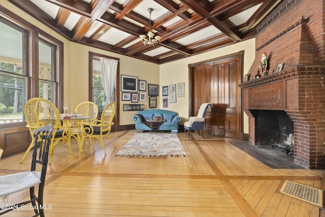 sitting room with a brick fireplace, ornamental molding, coffered ceiling, beam ceiling, and a notable chandelier