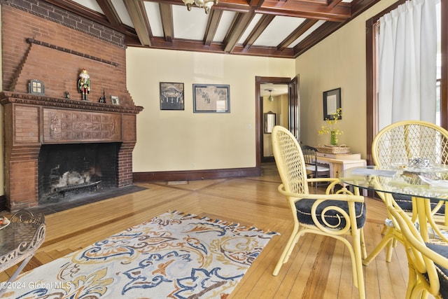 living room with beamed ceiling, wood-type flooring, and a brick fireplace