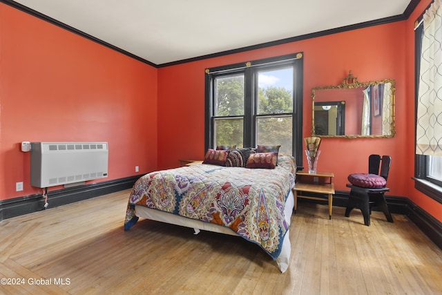 bedroom with light hardwood / wood-style floors, heating unit, and ornamental molding