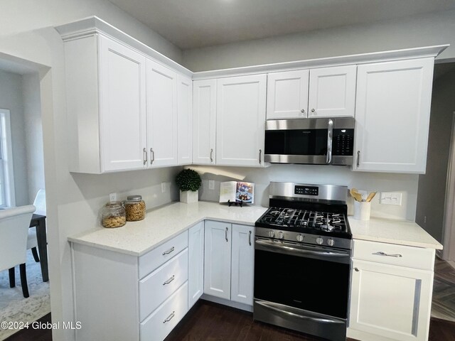 kitchen with dark hardwood / wood-style flooring, white cabinetry, and stainless steel appliances