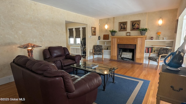 living area with a fireplace with flush hearth, baseboards, and wood finished floors