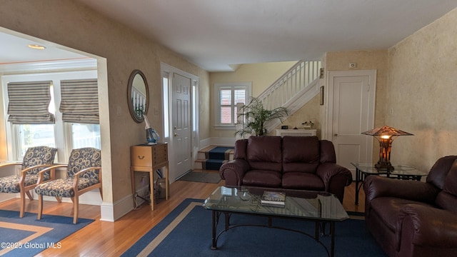 living room featuring baseboards, stairway, and wood finished floors