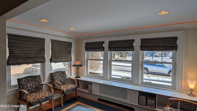 living area featuring radiator, crown molding, a wealth of natural light, and wood finished floors