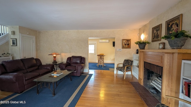 living room with wood finished floors, a fireplace with flush hearth, and baseboards