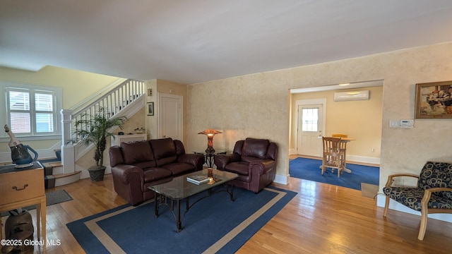 living area with stairs, an AC wall unit, and wood finished floors