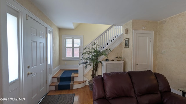 foyer entrance featuring baseboards, stairway, and wood finished floors