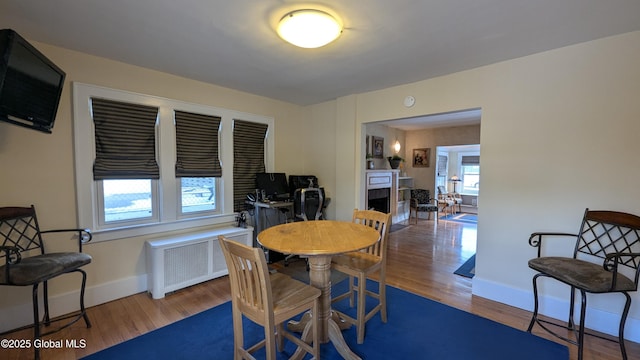 dining room with radiator, a fireplace, baseboards, and wood finished floors